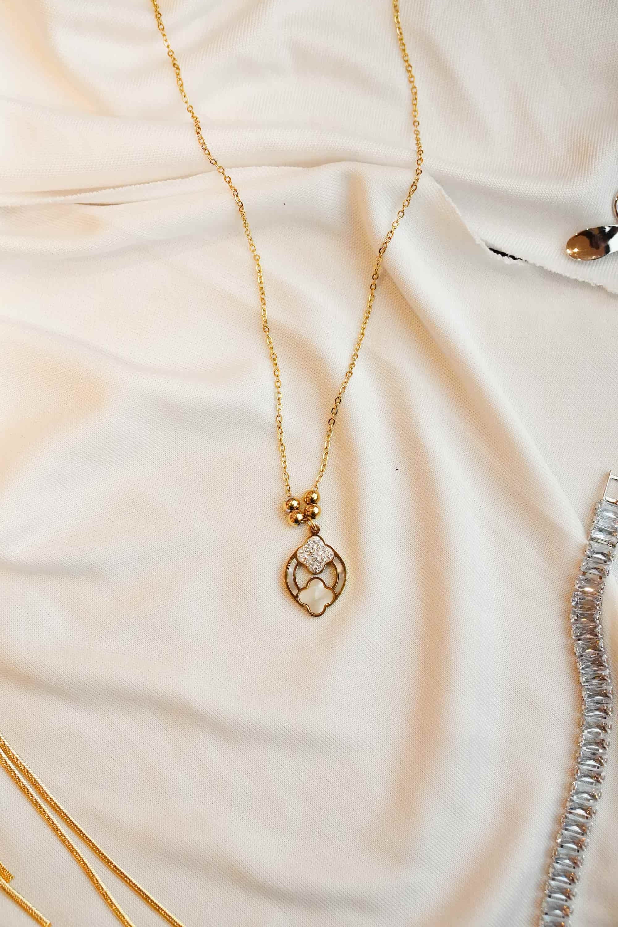 Gold ss necklace with a heart-shaped pendant on a soft fabric background