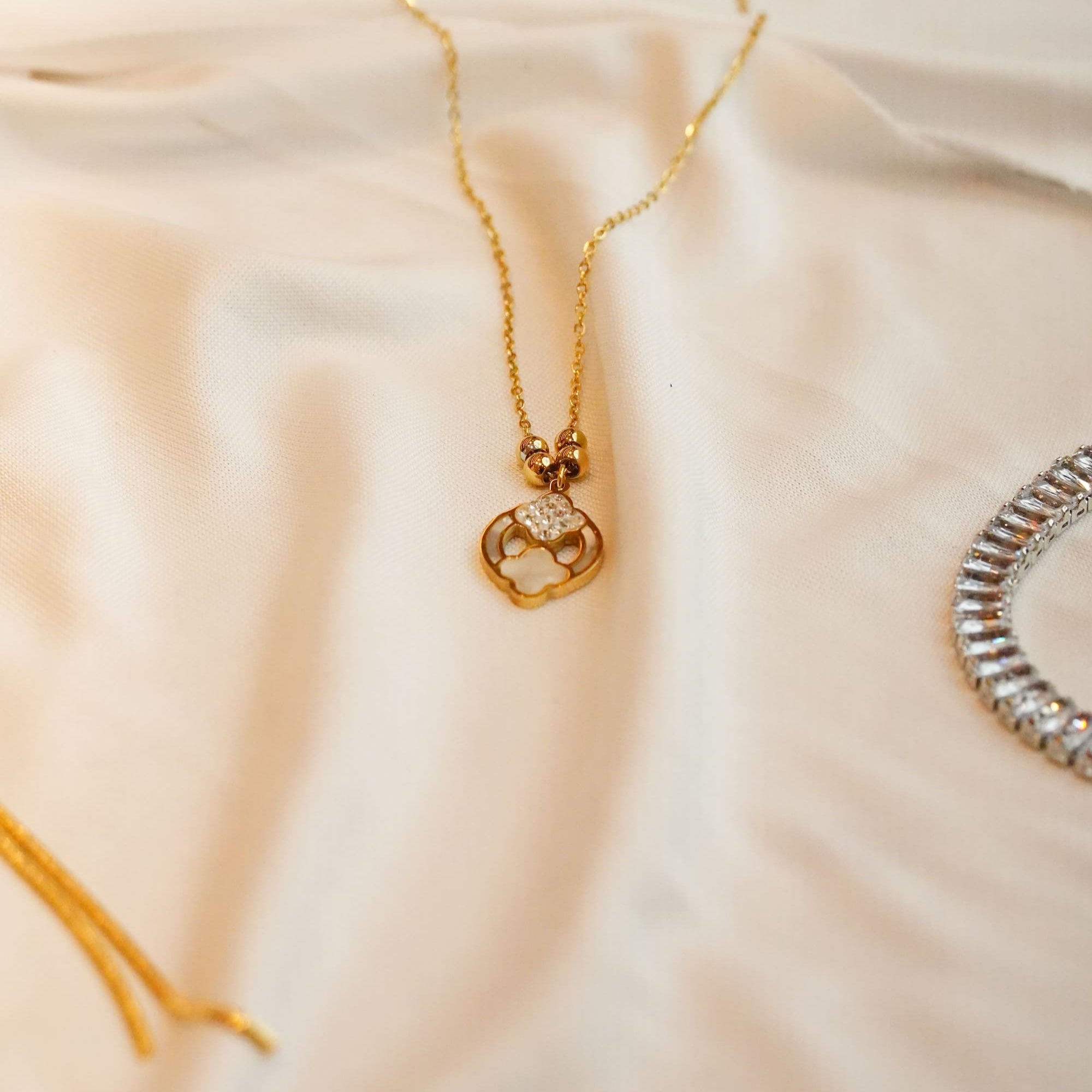 Gold ss necklace with a pendant on a soft beige fabric background