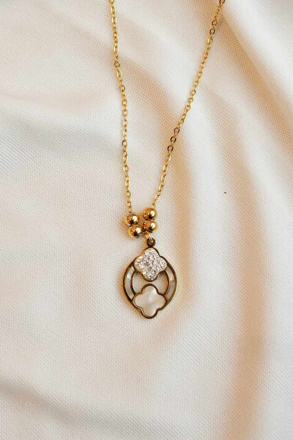 Gold ss necklace with a heart-shaped pendant on a soft fabric background