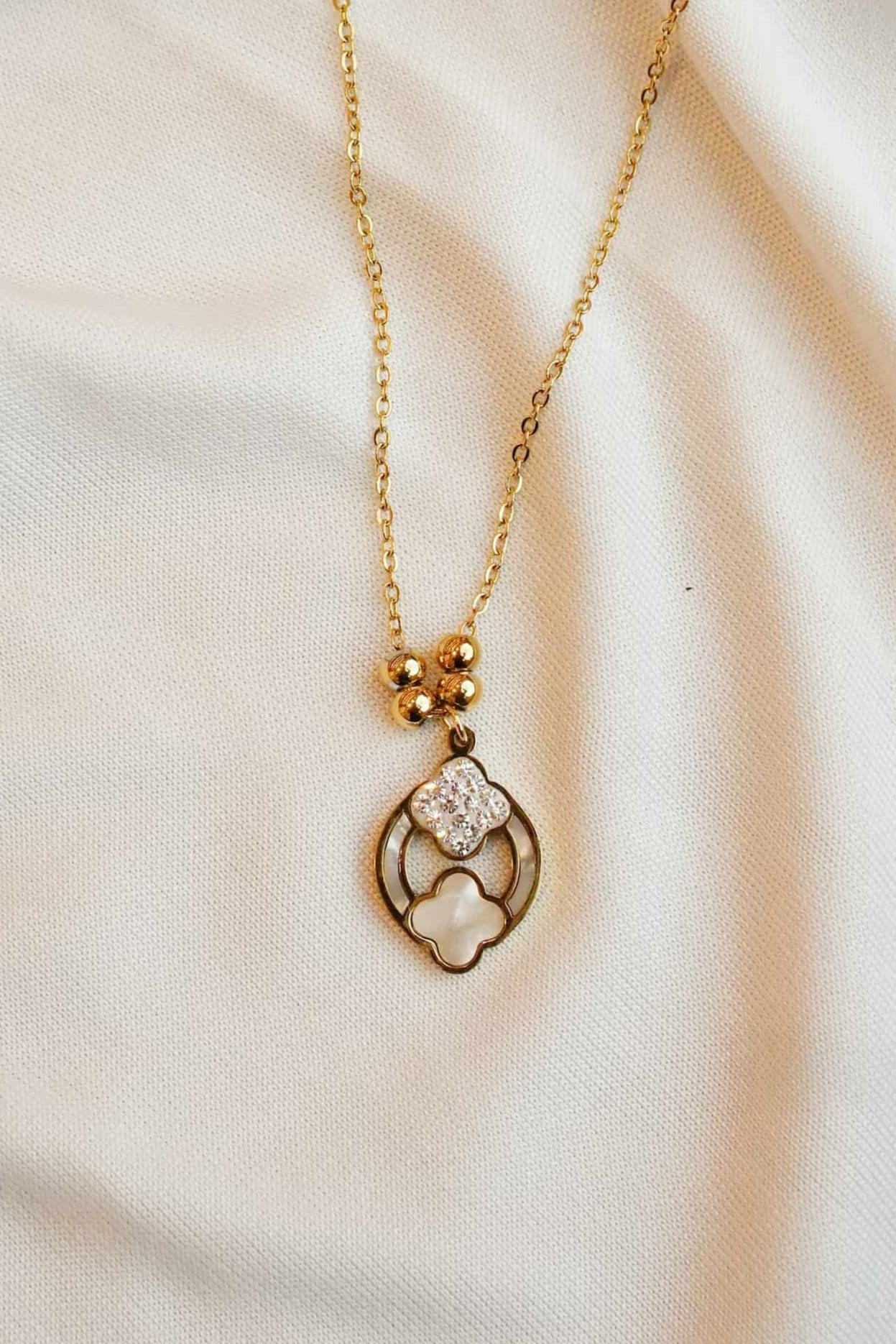 Gold ss necklace with a heart-shaped pendant on a soft fabric background