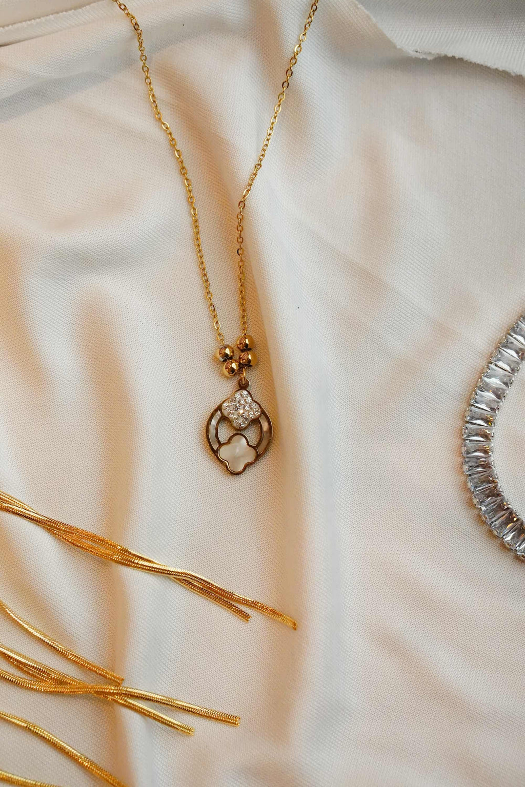 Gold ss necklace with a decorative clasp on a soft beige fabric background