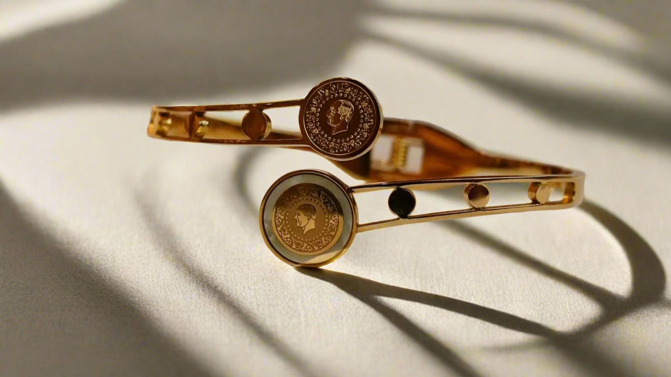 Gold ss bracelet with circular designs on a textured beige surface