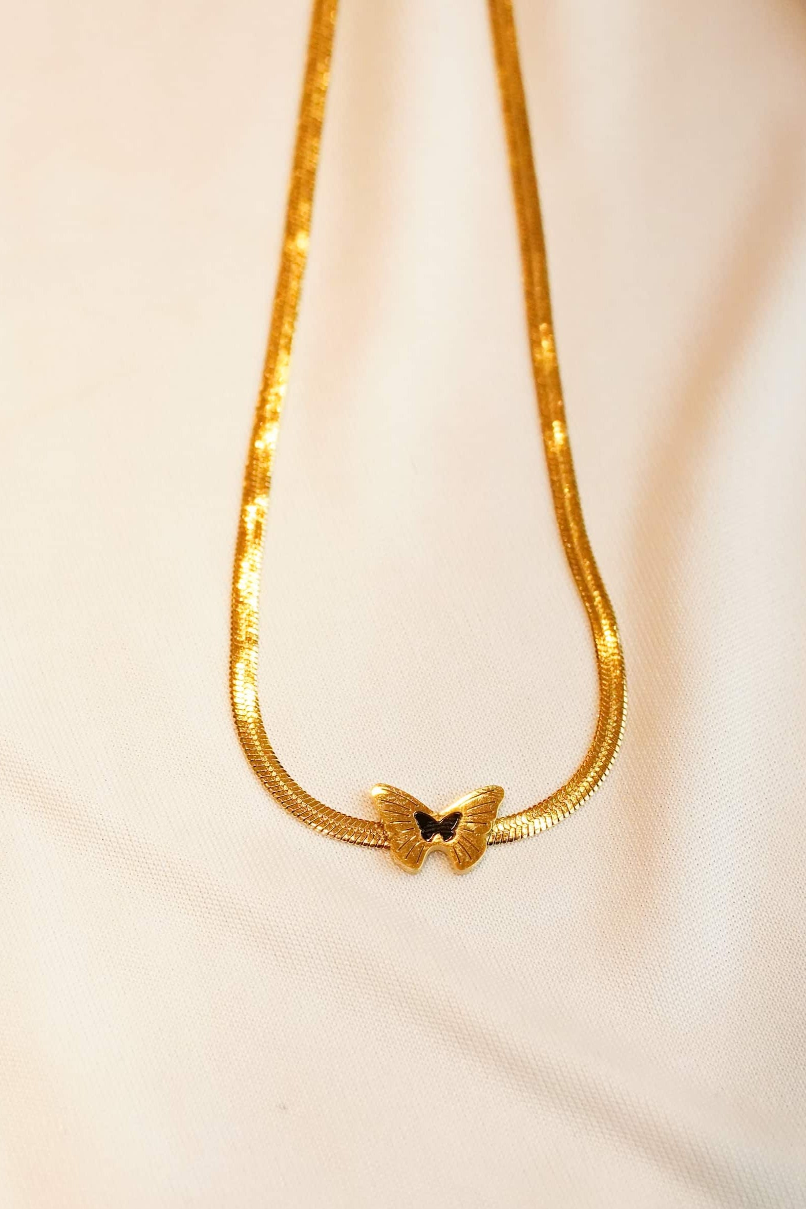 Gold ss necklace with a bow pendant on a soft beige background