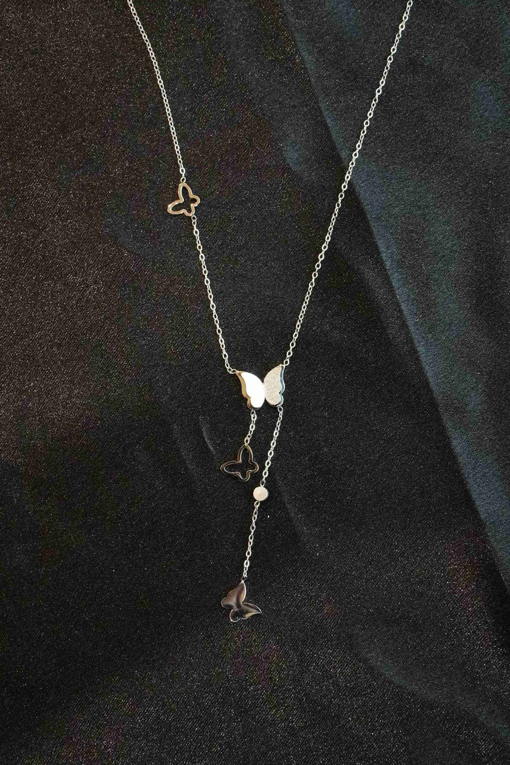 Necklace with butterfly-shaped pendants on a dark fabric background
