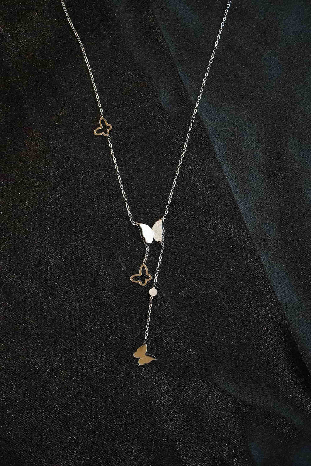 Necklace with butterfly pendants on a dark fabric background