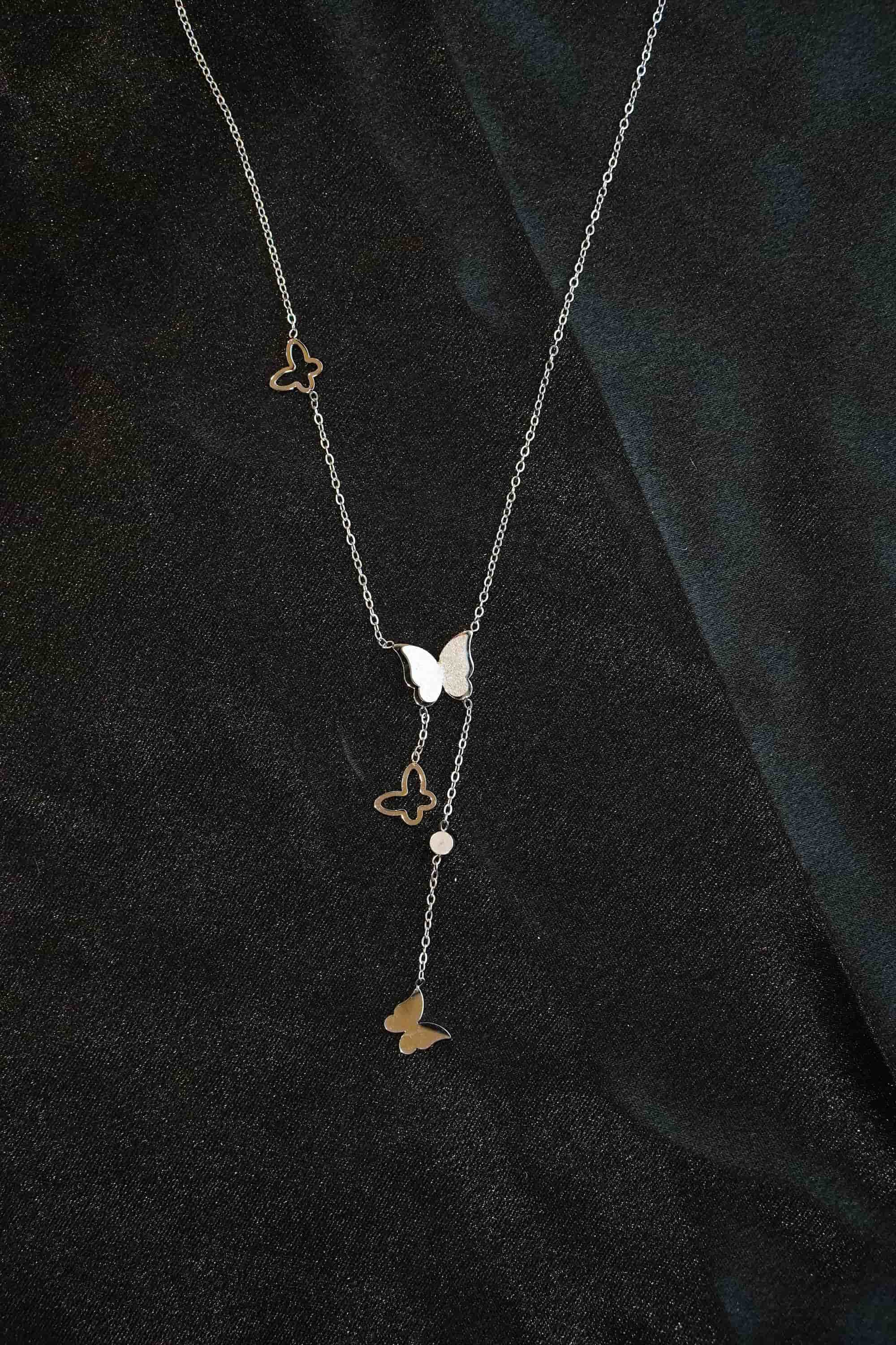 Necklace with butterfly pendants on a dark fabric background