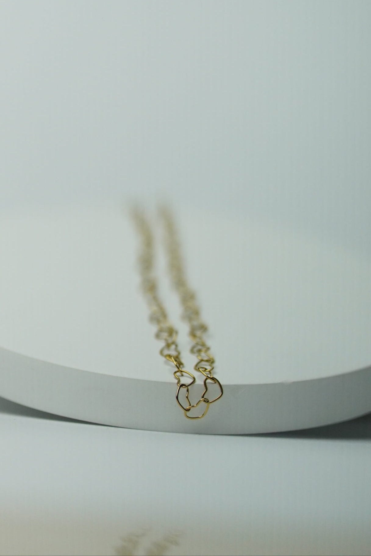Gold necklace on a white stand with a light gray background